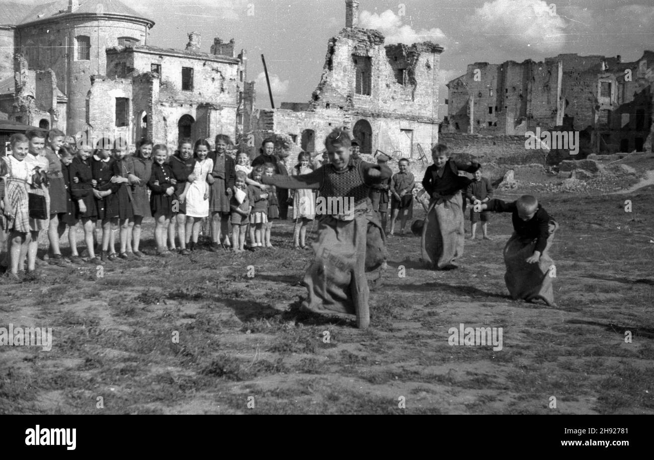 Warszawa, 1947-05. Nowe Miasto, uczniowie szko³y powszechnej przy parafii œw. Franciszka z ASY¿u (Serafickiego). Nz. Dzieci podczas zabawy - wyœcig w workach. W tle z lewej ruiny koœcio³a franciszkanów. bk/gr PAP Dok³adny dzieñ wydarzenia nieustalony. Varsavia, maggio 1947. La Città Nuova, alunni della scuola pubblica parrocchiale di San Francesco d'Assisi. Nella foto: Bambini durante un gioco - una corsa in sacchi. Sullo sfondo a sinistra le rovine della chiesa francescana. bk/gr PAP Foto Stock