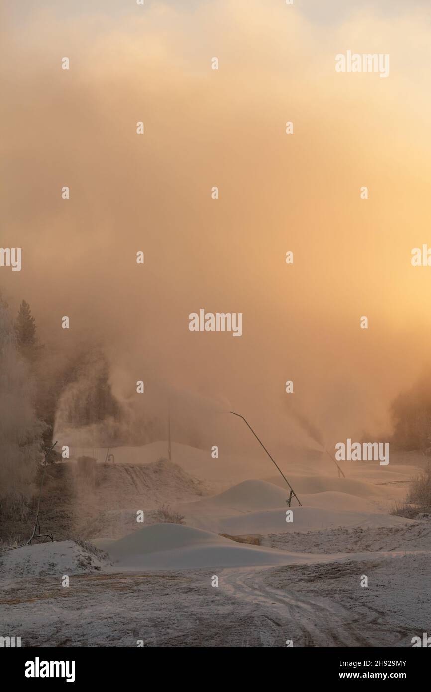 La visibilità diminuisce quando le macchine per la neve spruzzano una nube di neve sul pendio Foto Stock
