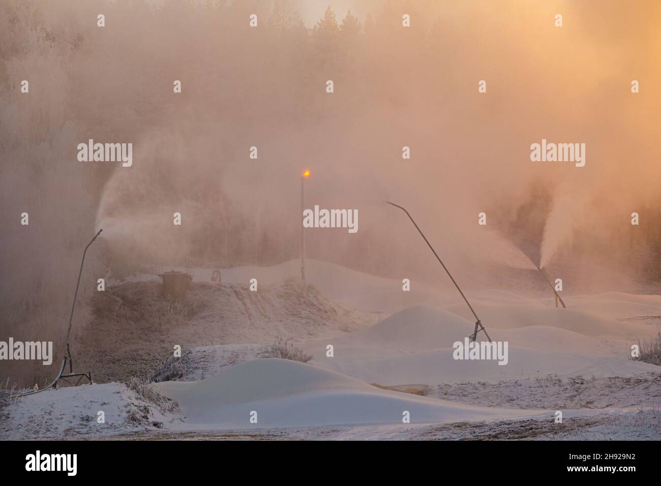 La visibilità diminuisce quando le macchine per la neve spruzzano una nube di neve sul pendio Foto Stock