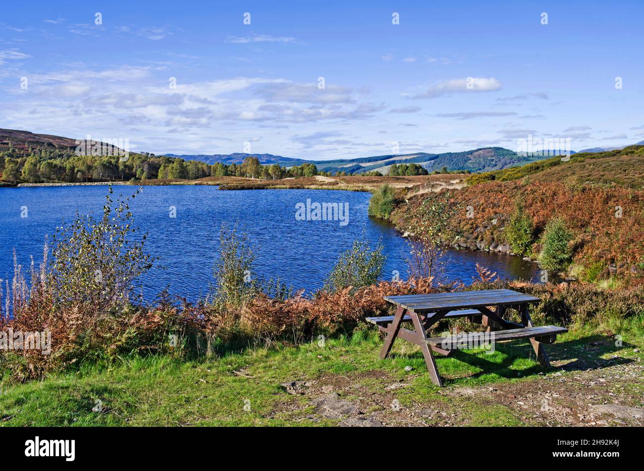 Tavolo da picnic in un piccolo lago di montagna sulla brughiera, inizio autunno, Highland Perthshire, Scozia Regno Unito Foto Stock