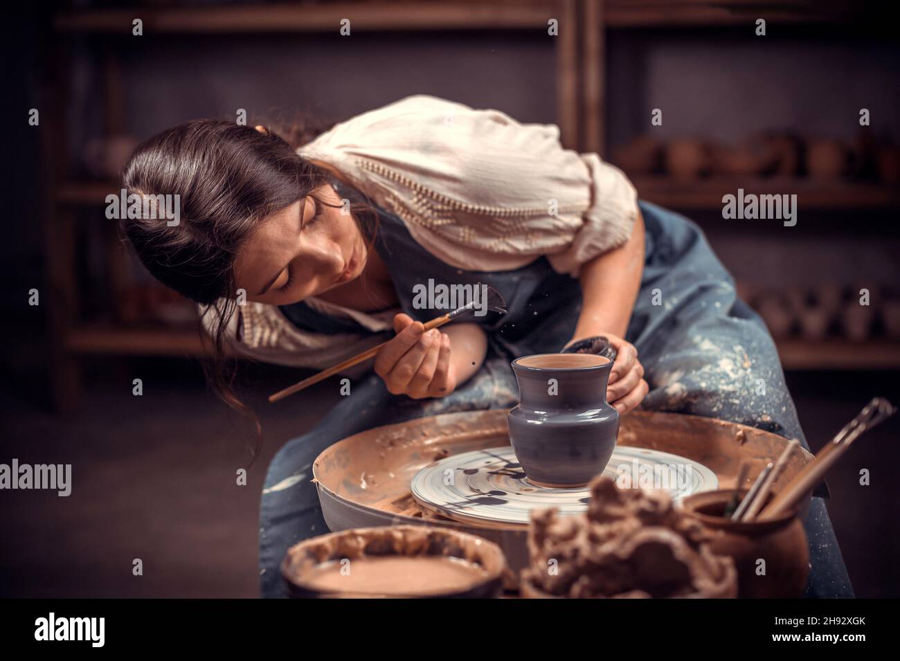 Bella giovane donna maestro dimostra il processo di produzione di piatti in ceramica utilizzando la vecchia tecnologia. Artigianato popolare. Foto Stock