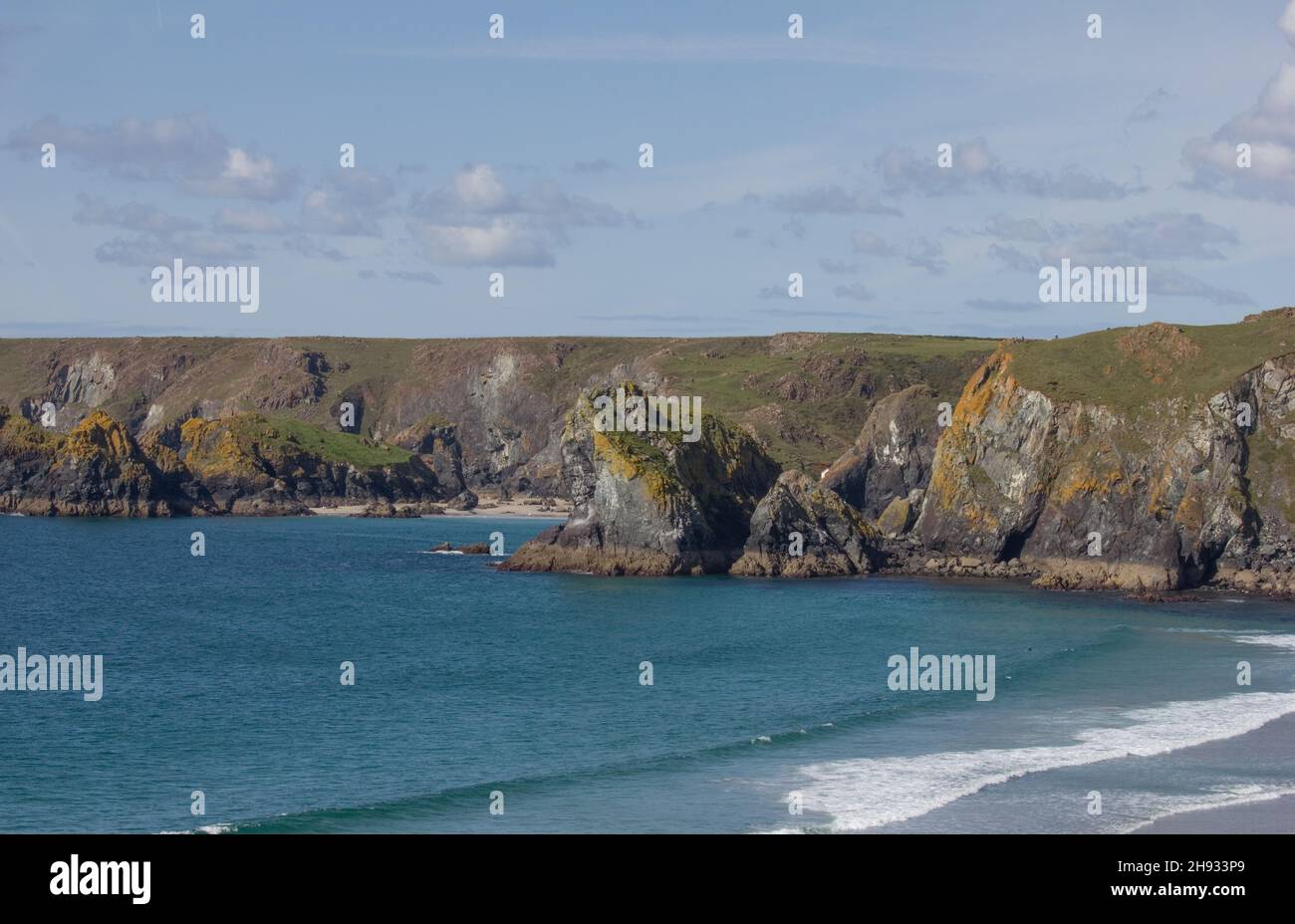 La roccia del Leone vista dal sentiero costiero della Cornovaglia con Kynance Cove e Asparagus Island oltre. Spiaggia di Pentreath in primo piano. Foto Stock