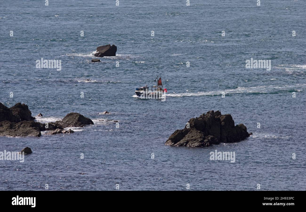 Piccola barca da pesca che passa attraverso le Maenheere Rocks al largo di Lizard Point, Cornovaglia, Inghilterra. La nave della White Star Line SS Suevic si è incagliata qui. Foto Stock