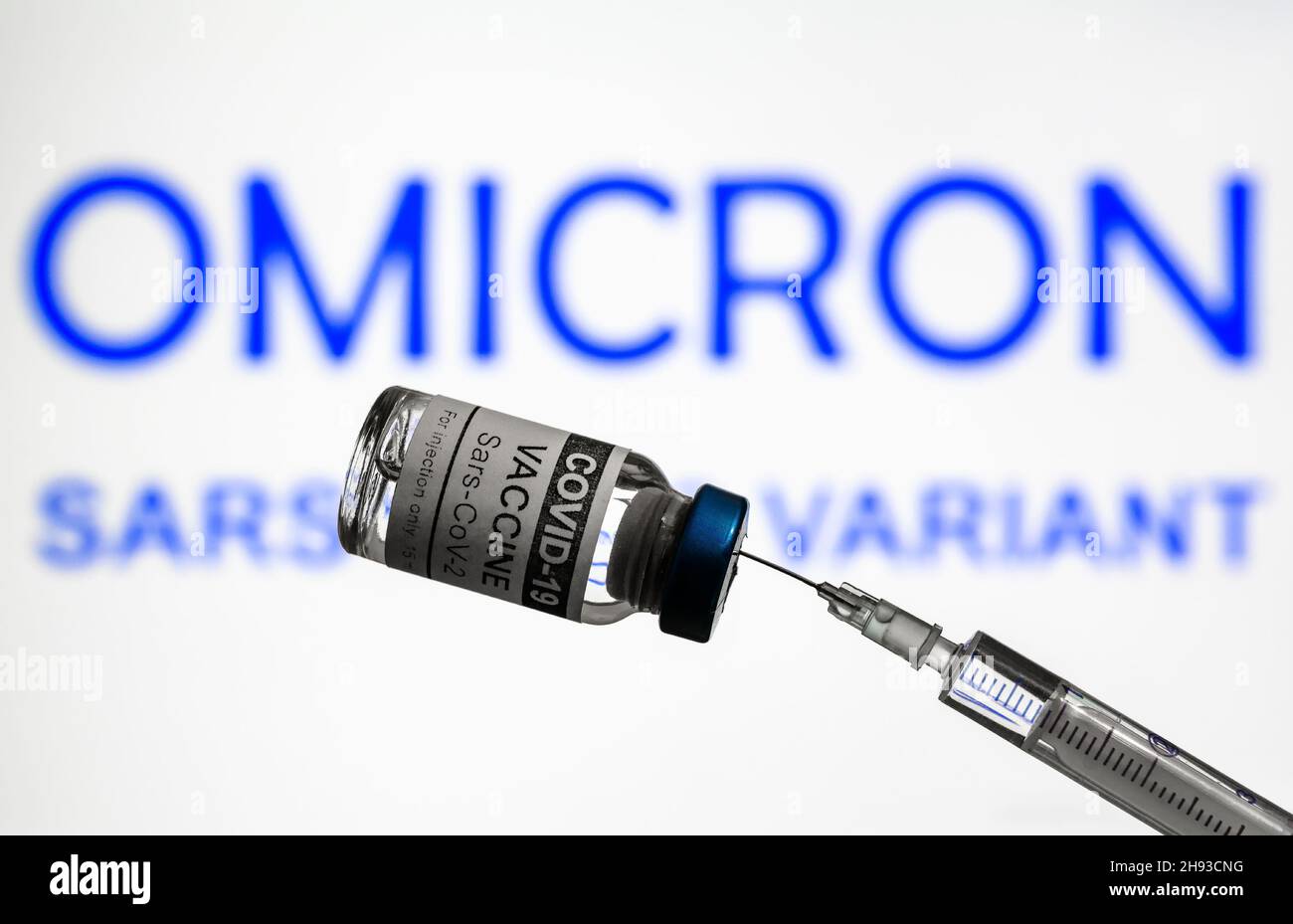Vaccino e siringa COVID-19 sullo sfondo delle informazioni sulla variante Omicron, focalizzazione sul flacone di vaccino per coronavirus. Concetto di nuovi ceppi di virus corona, vaccino Foto Stock