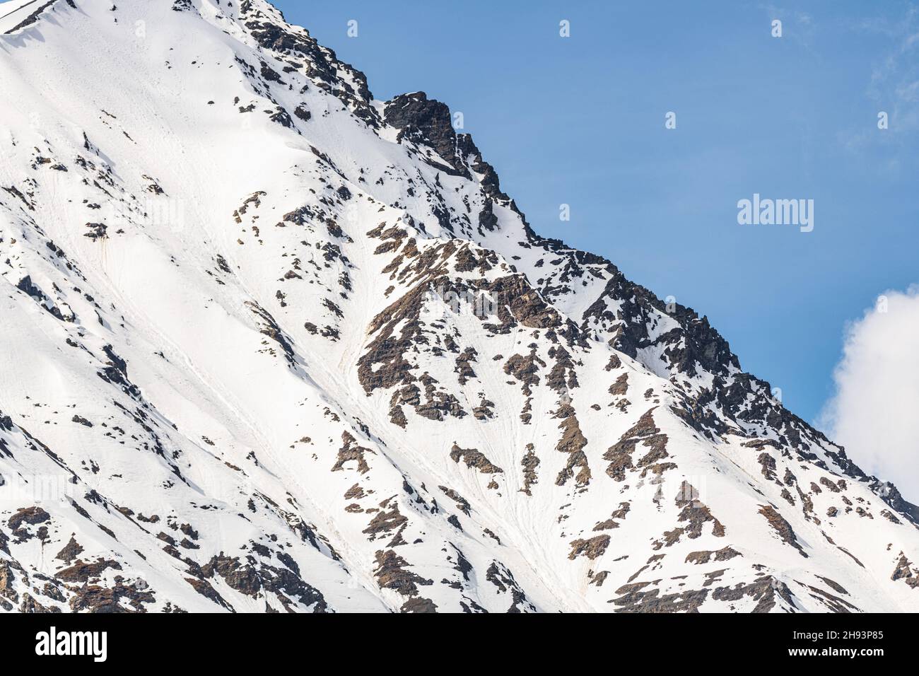 Splendida montagna innevata con sfondo blu cielo, frastagliato bordo di picco. Sfondo irreale, vista panoramica per desktop, foto di sfondo. Foto Stock