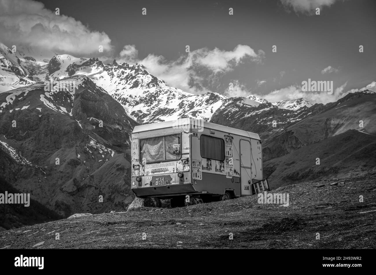 Vecchio furgone abbandonato contro le montagne del Caucaso maggiore nel comune di Stepantsminda (Kazbegi). Regione di Mtskheta-Mtianeti, Georgia. Bianco e nero. Foto Stock