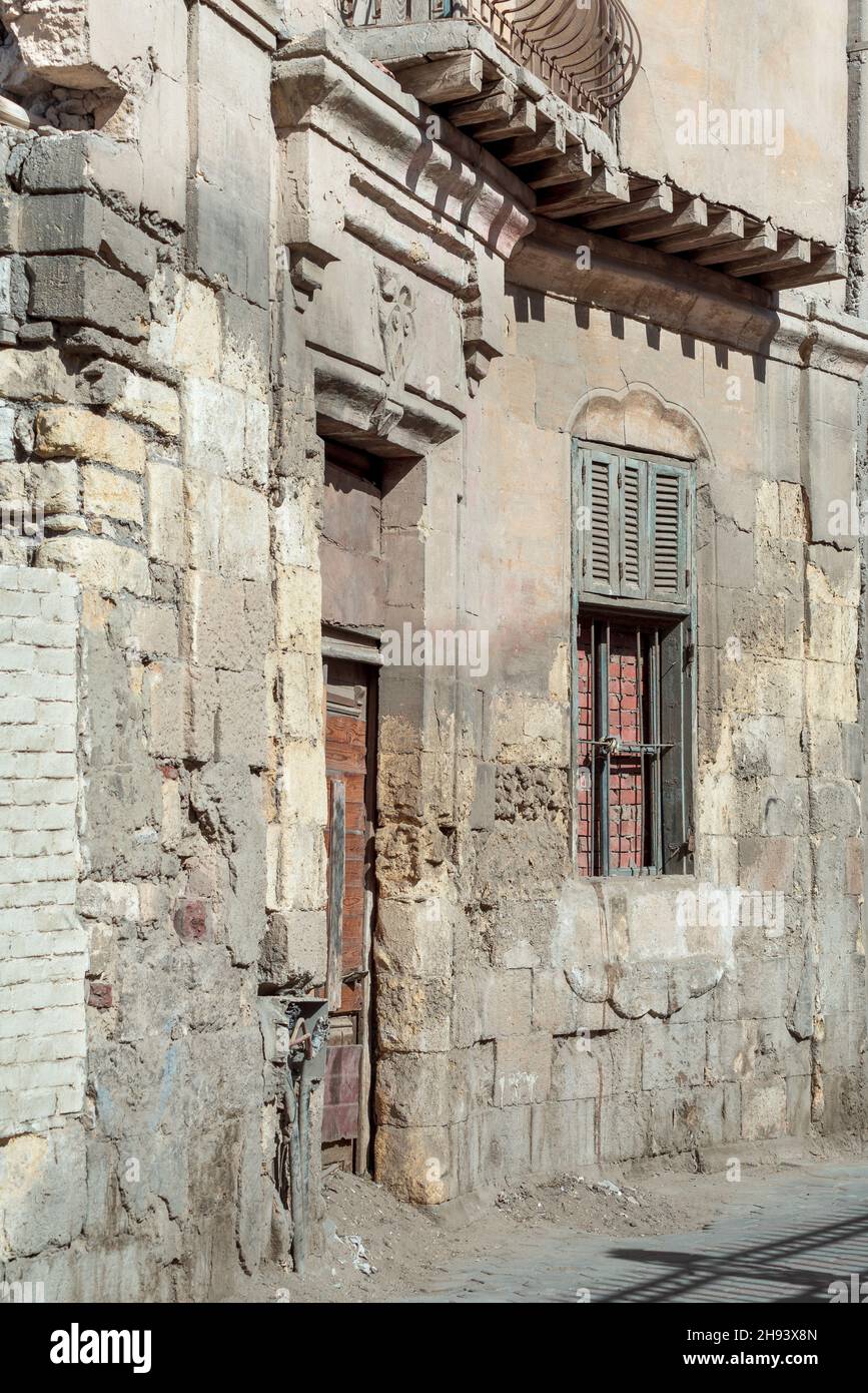 Muro di mattoni di pietra grunge con porta di legno rotto e chiuso rotto finestra nel quartiere abbandonato Foto Stock