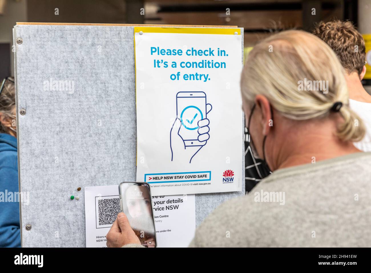 L'uomo australiano utilizza il suo iPhone per eseguire la scansione del codice QR e il check-in presso i locali come richiesto a causa della pandemia del codice 19 come nuova variante omicron è scoperta. Foto Stock