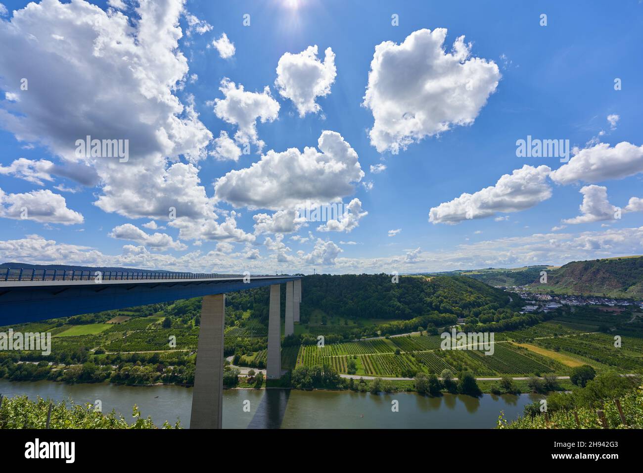 Bel ponte della Valle Mosella in acciaio blu e colonne grigie, grandi alberi sullo sfondo, cielo blu con nuvole bianche e grigie. Germania. Foto Stock