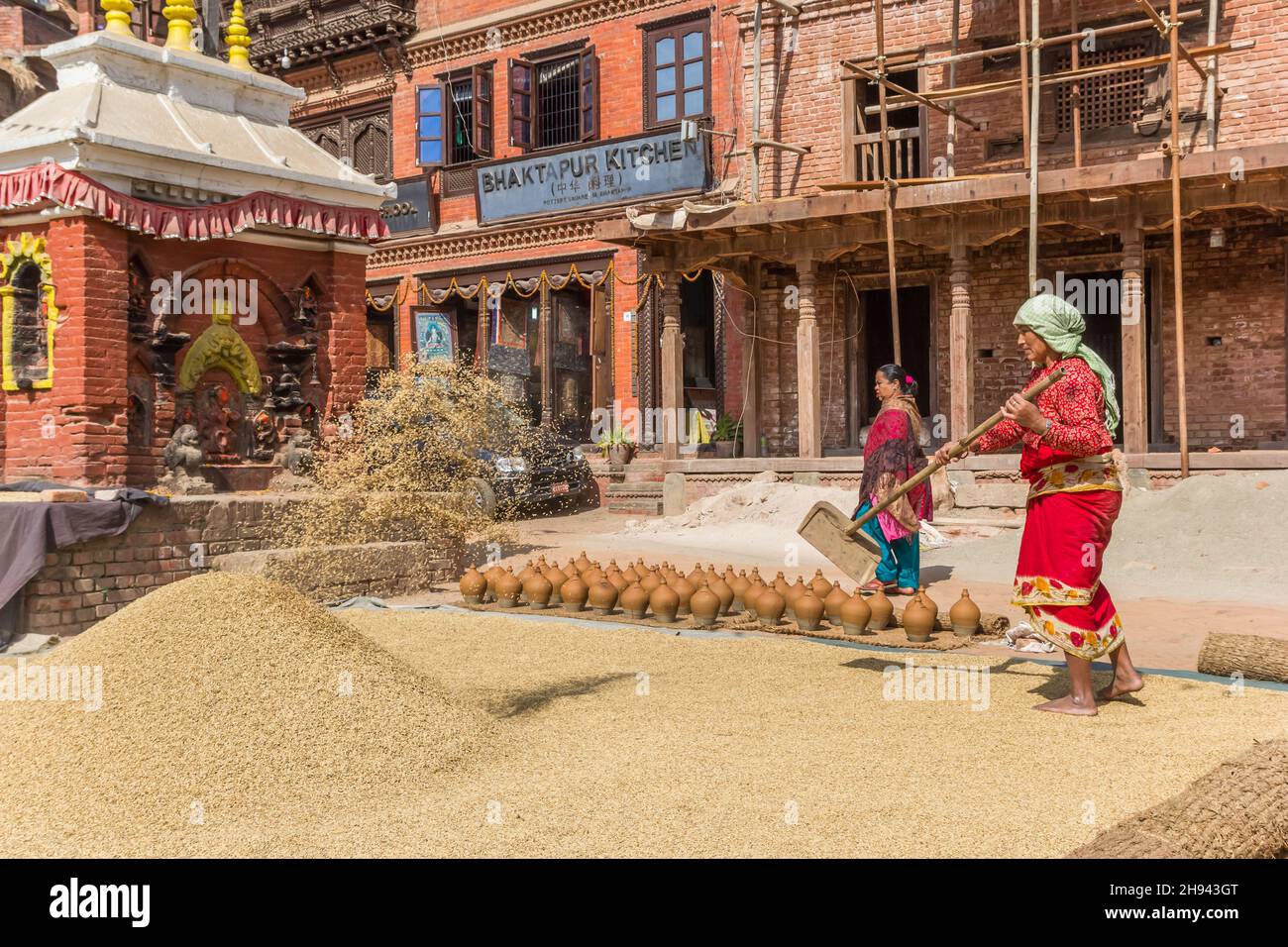 Donna che asciuga il riso alla piazza della ceramica di Bhaktapur, Nepal Foto Stock