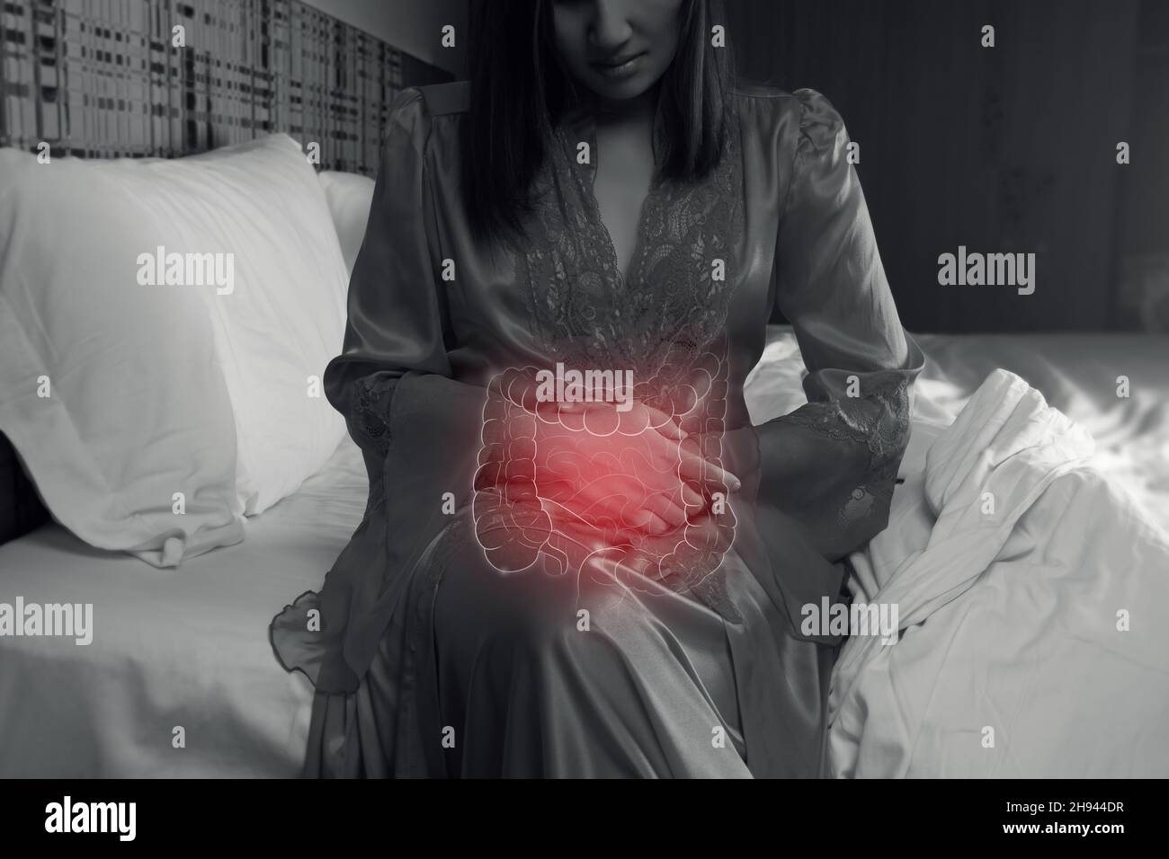 Donna asiatica in pelle di raso che ha mal di stomaco di notte. Foto Stock