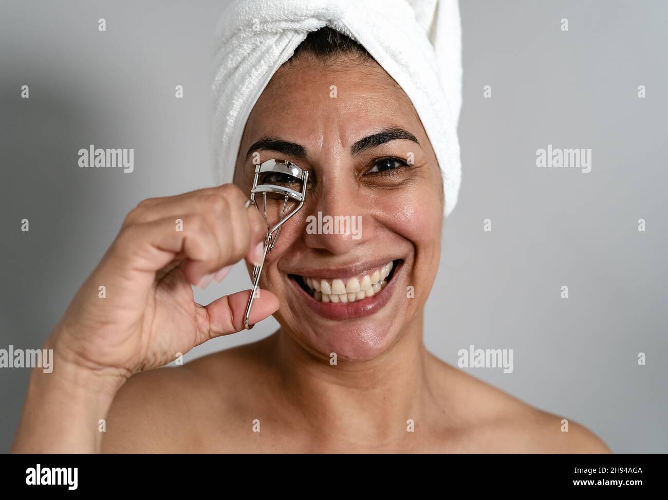 Happy Latin maturo donna utilizzando eyelash Curler - persone bellezza e benessere stile di vita concetto Foto Stock