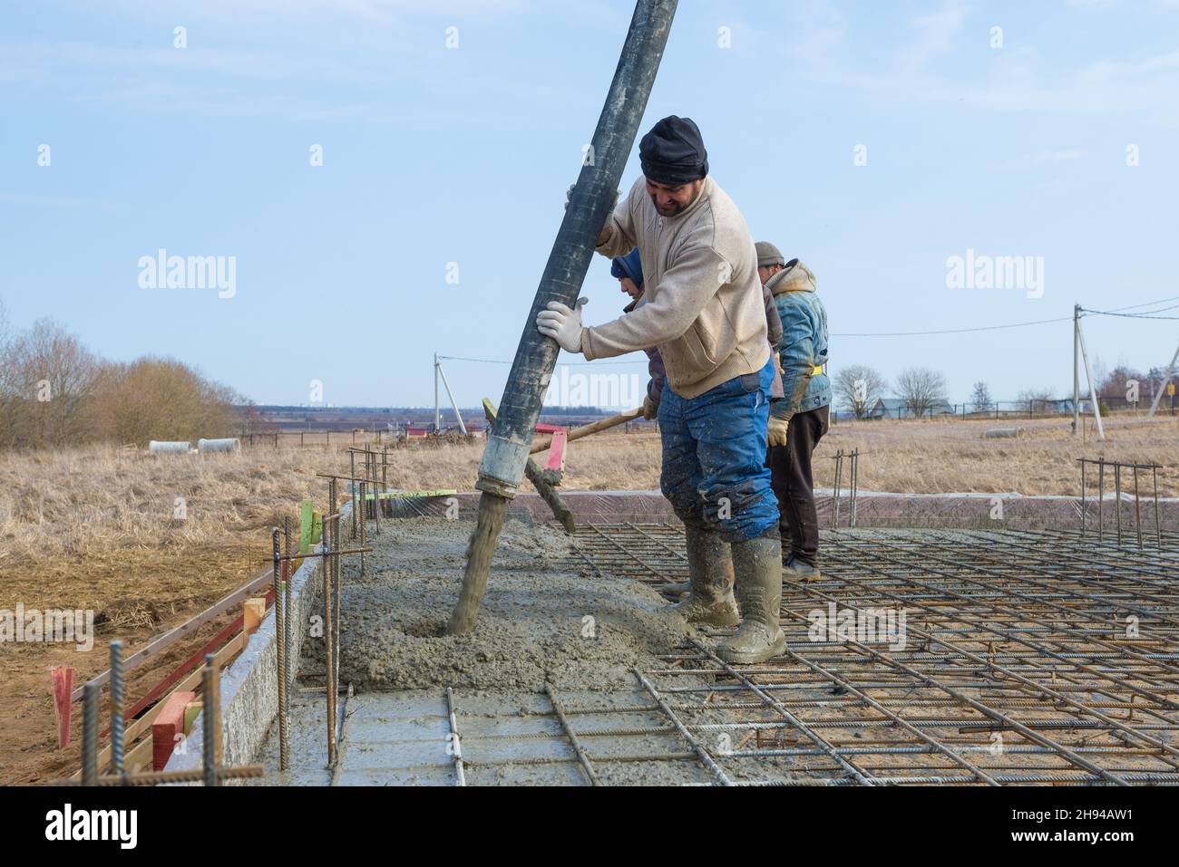 REGIONE DI LENINGRAD, RUSSIA - 28 MARZO 2021: I lavoratori dei costruttori e dei migranti stanno gettando le basi per la costruzione di un casolare di campagna Foto Stock