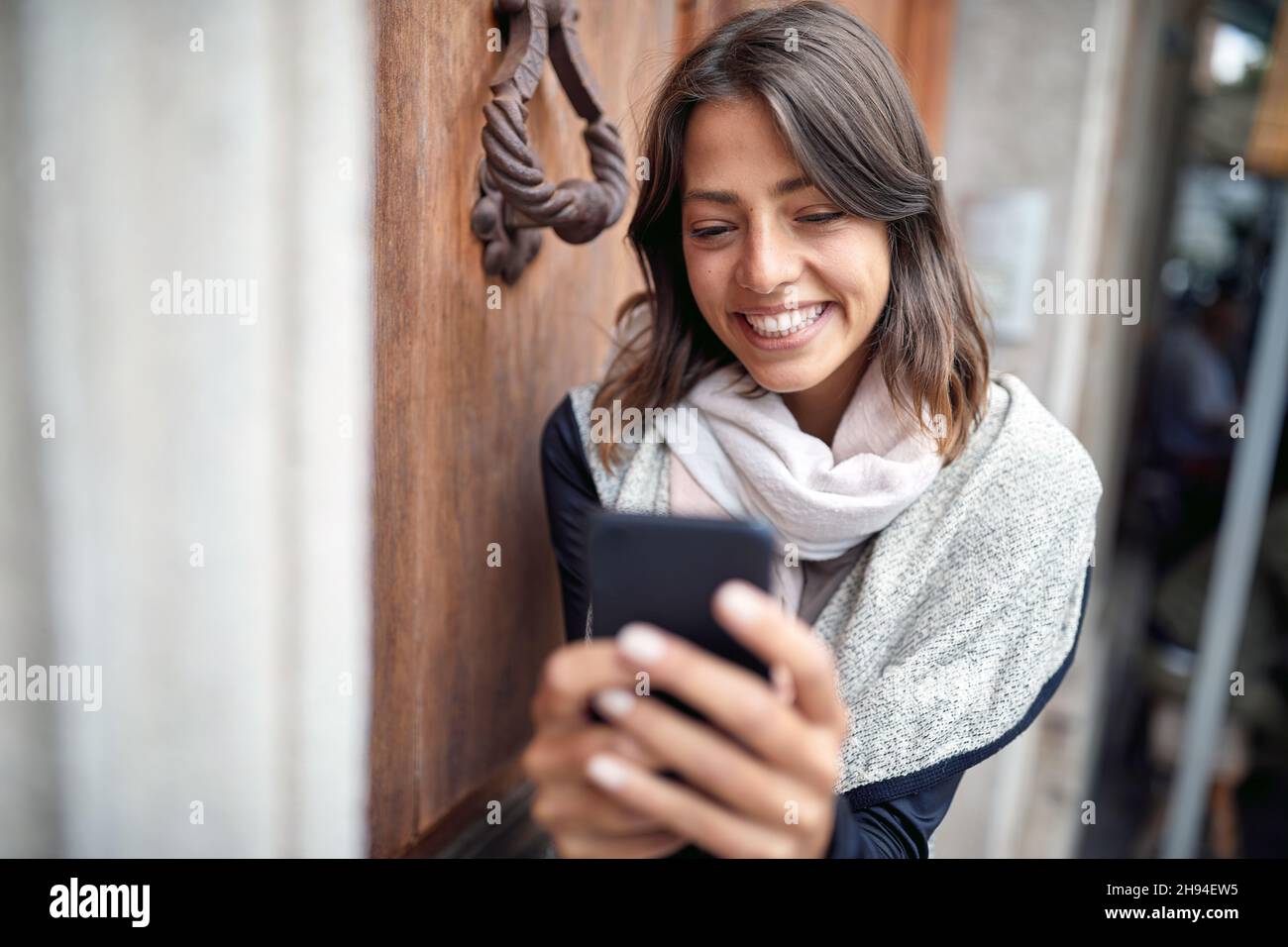 Primo piano di una giovane donna attraente in piedi di fronte all'ingresso dell'edificio e testando in un buon umore. Passeggiata, città Foto Stock