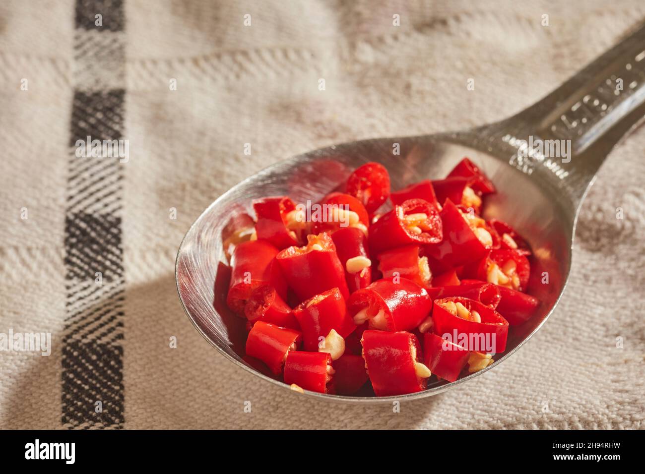 Un cucchiaio di peperoncini rossi thailandesi tritati e freschi Foto Stock