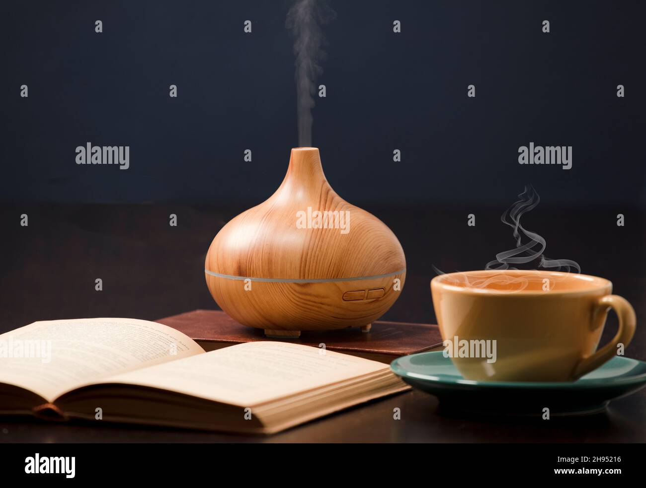 Relax a casa con olio aromatherapy diffusore, tè giallo, libro aperto. Aroma essenza di salute, benessere aromaterapia casa aromatico tranquillo Th Foto Stock