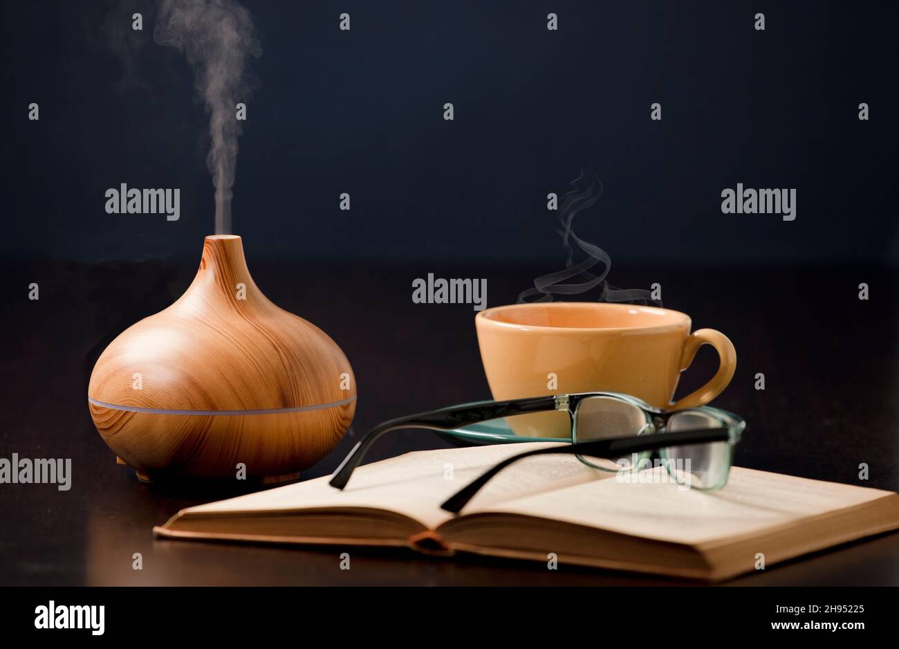 Relax a casa con olio aromatherapy diffusore, tè giallo, libro aperto. Aroma essenza di salute, benessere aromaterapia casa aromatico tranquillo Th Foto Stock
