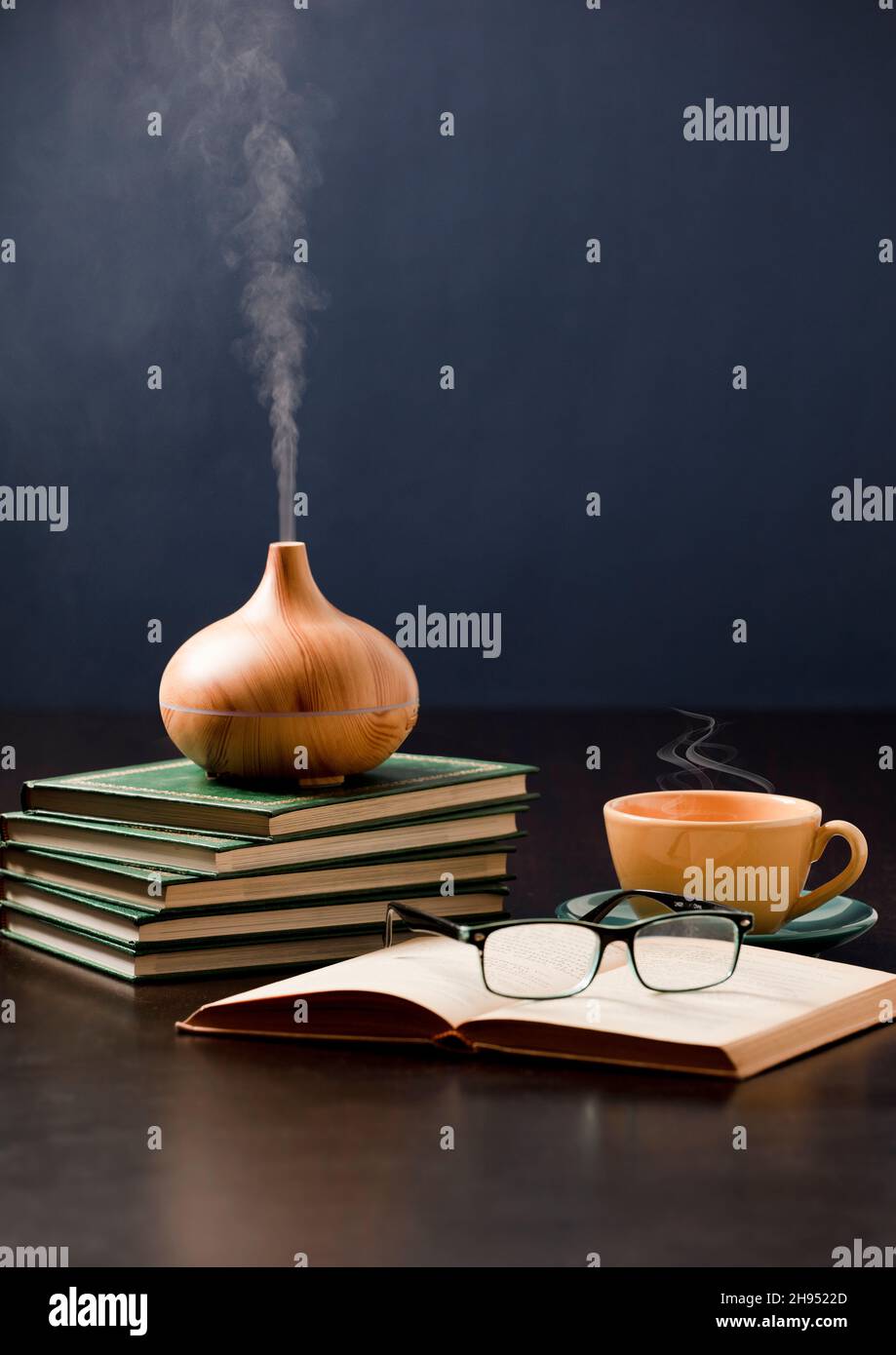 Relax a casa con olio aromatherapy diffusore, tè giallo, libro, bicchieri da lettura. Aroma essenza di salute, benessere aromaterapia casa aromatica Foto Stock