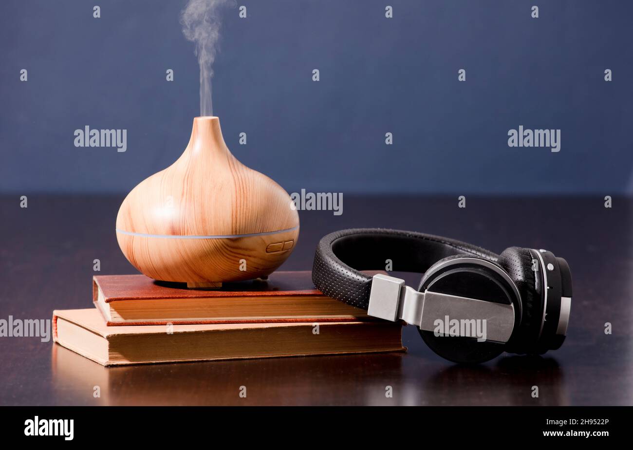 Relax a casa con olio aromatherapy diffusore e cuffie con libro. Aroma essenza di salute, benessere aromaterapia casa aromatico tranquillo tero Foto Stock