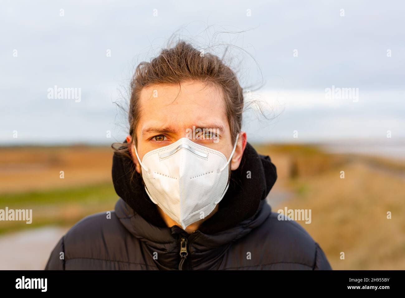 Un giovane uomo che indossa una maschera KN95 ad uso singolo durante la pandemia del virus della corona di Covid-19 Foto Stock