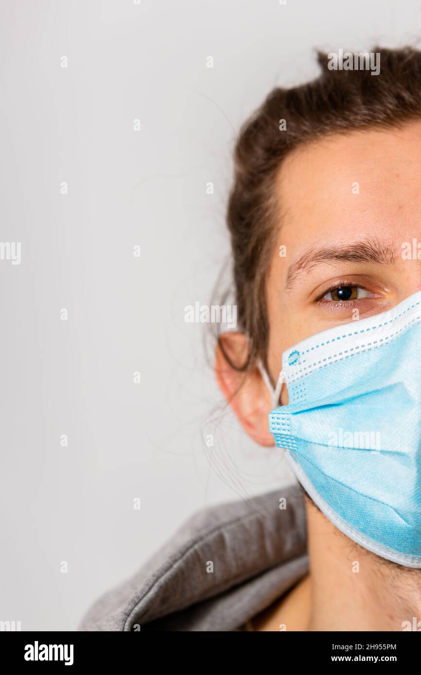 Un giovane uomo che indossa una maschera medica durante la pandemia del virus della corona di Covid-19 Foto Stock