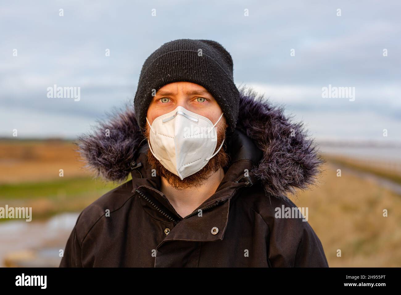 Un giovane uomo che indossa una maschera KN95 ad uso singolo durante la pandemia del virus della corona di Covid-19 Foto Stock