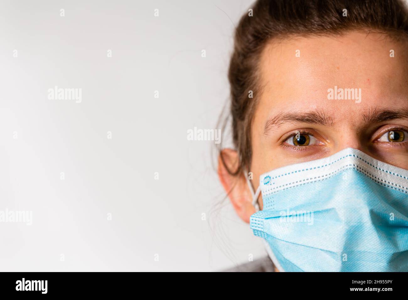 Un giovane uomo che indossa una maschera medica durante la pandemia del virus della corona di Covid-19 Foto Stock