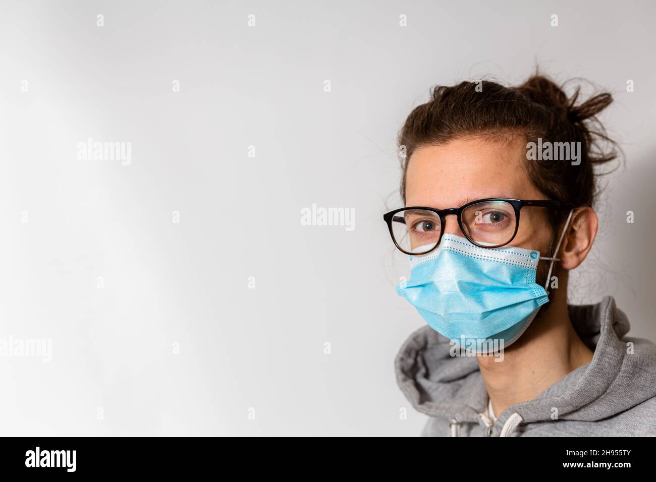 Un giovane uomo in occhiali che indossa una maschera medica uno uso durante la pandemia del virus della corona Covid-19 Foto Stock