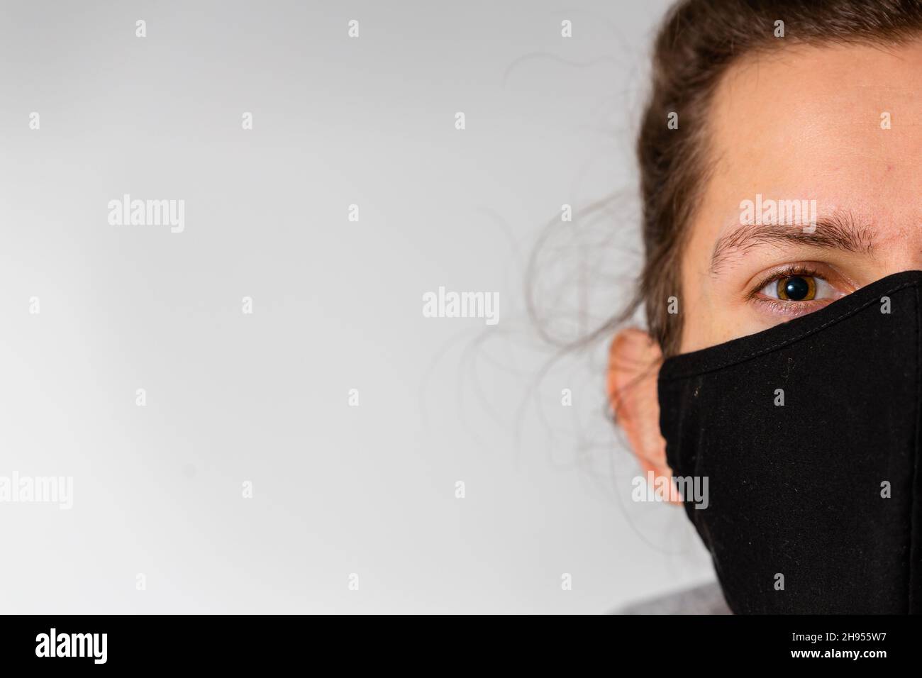 Un giovane uomo che indossa una maschera nera lavabile durante la pandemia del virus della corona di Covid-19 Foto Stock
