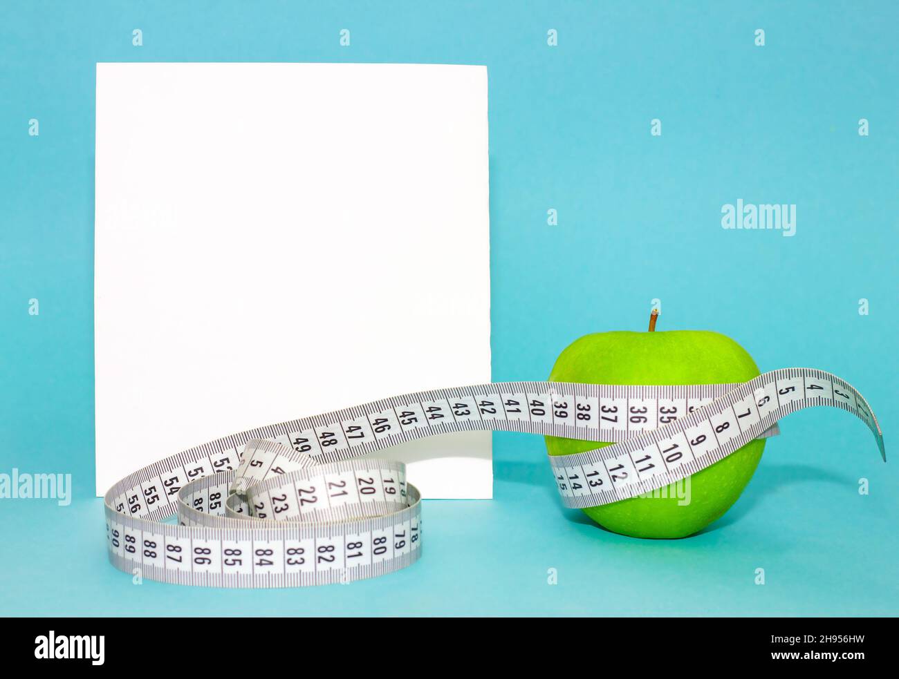 Primo piano del nastro verde di mela centimetro su sfondo blu per la progettazione concettuale. Stile di vita, concetto di cibo Foto Stock