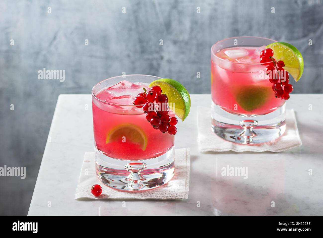 Cocktail con cocktail Caipirinha al ribes rosso con lime e contorno di Berry sul piano minimal Marble Counter Top Foto Stock