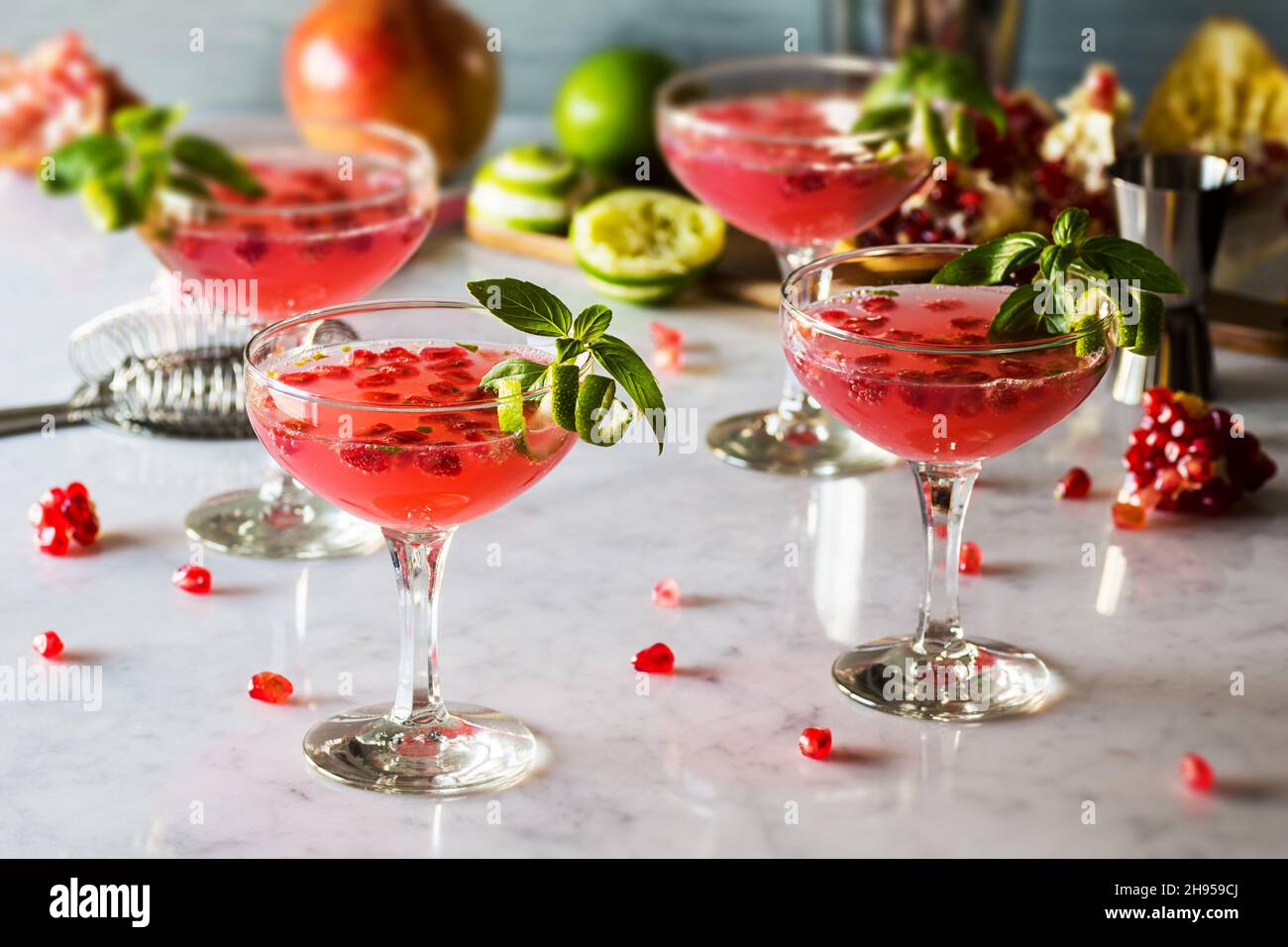 Melagrana cocktail Basil Martini con Lime Twist in bicchieri Coupé sul banco marmo Foto Stock