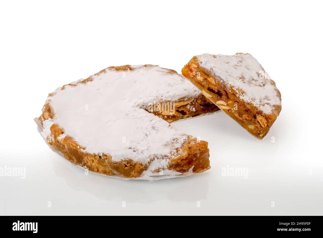 Panforte di Siena, tradizionale dolce natalizio con mandorle, scorza d'arancia e spezie toscane, italia. Torta con fetta isolata su bianco Foto Stock