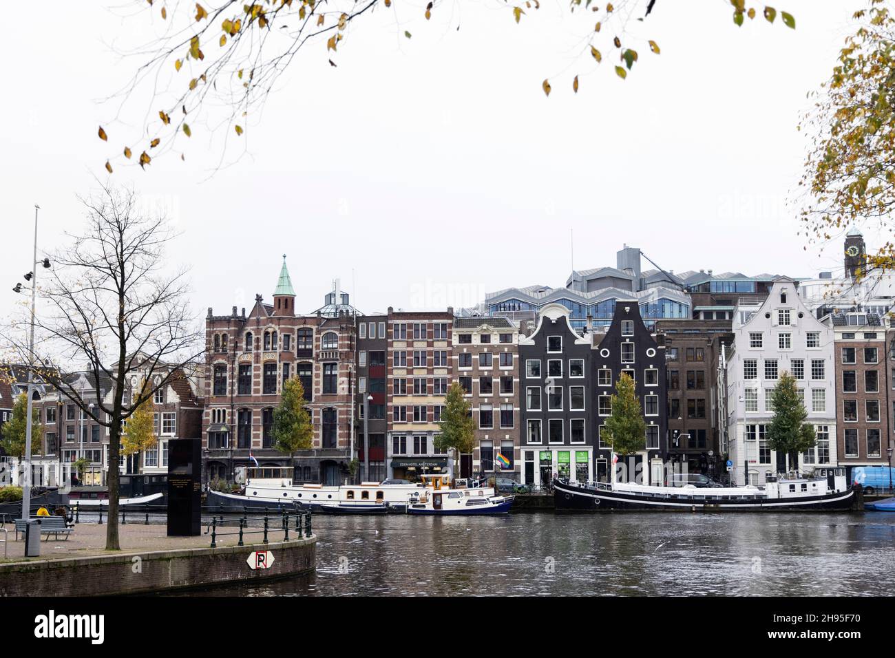 Edifici storici tradizionali e case galleggianti sull'Amstel in un giorno autunnale ad Amsterdam, Paesi Bassi. Foto Stock