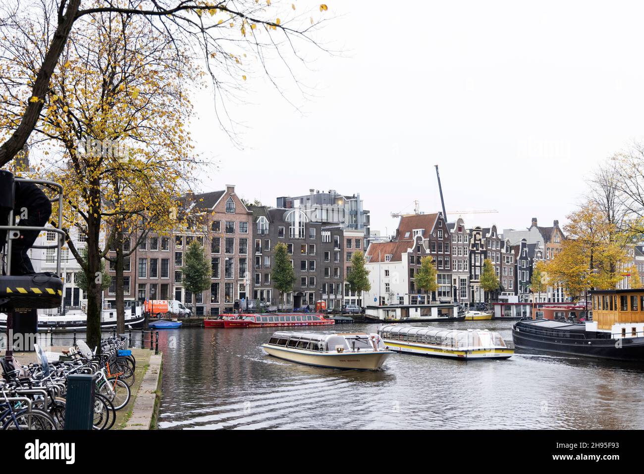 Edifici storici tradizionali e tour in barca sull'Amstel in un giorno autunnale ad Amsterdam, Paesi Bassi. Foto Stock