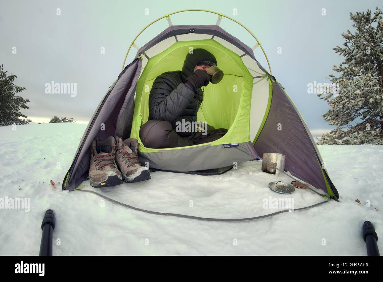 inverno campeggio selvaggio sulla neve un uomo che beve nella tenda Foto Stock