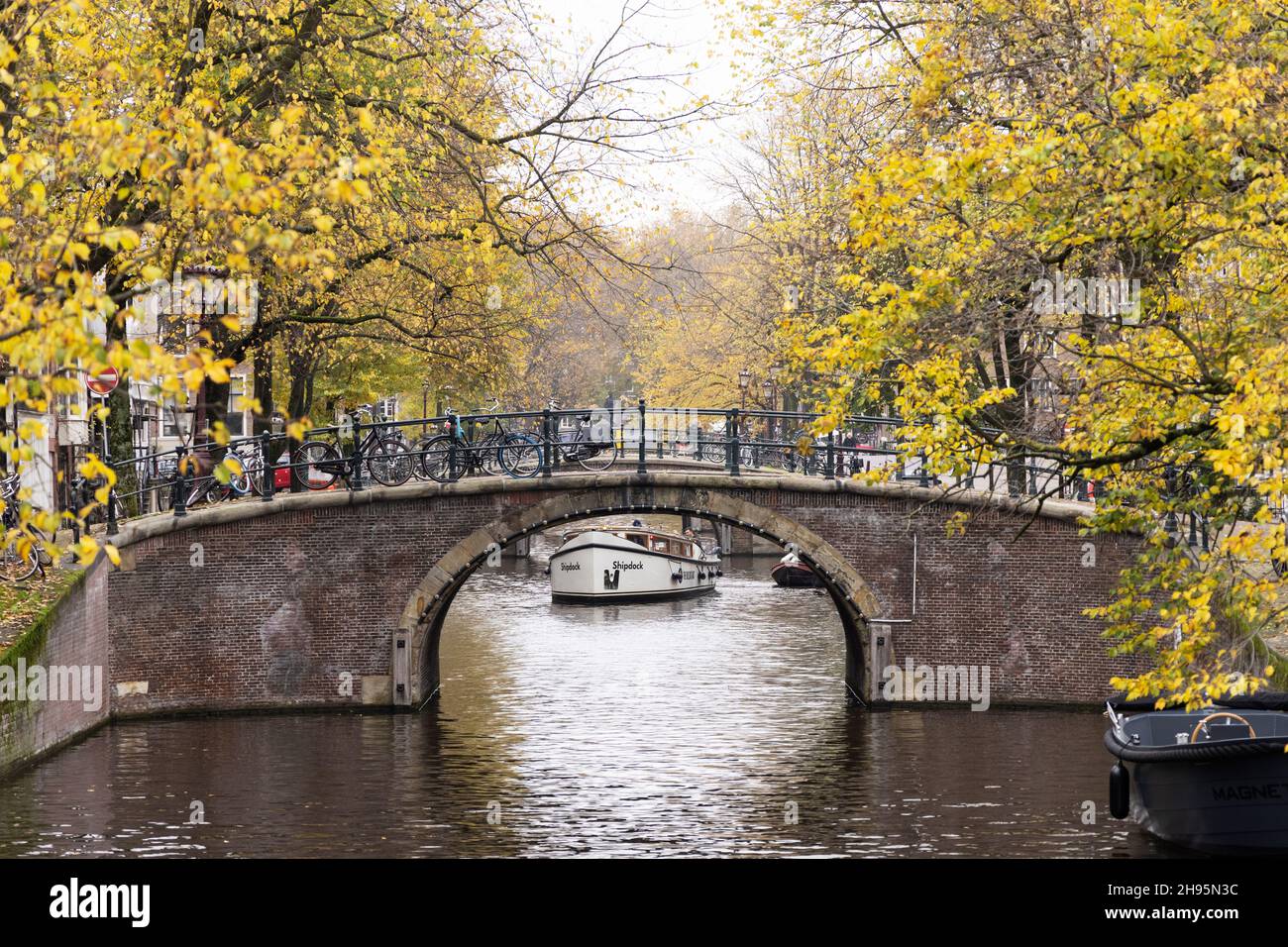 Una barca è visibile sotto uno dei sette ponti del canale Reguliersgracht ad Amsterdam, Paesi Bassi, il giorno di novembre. Foto Stock