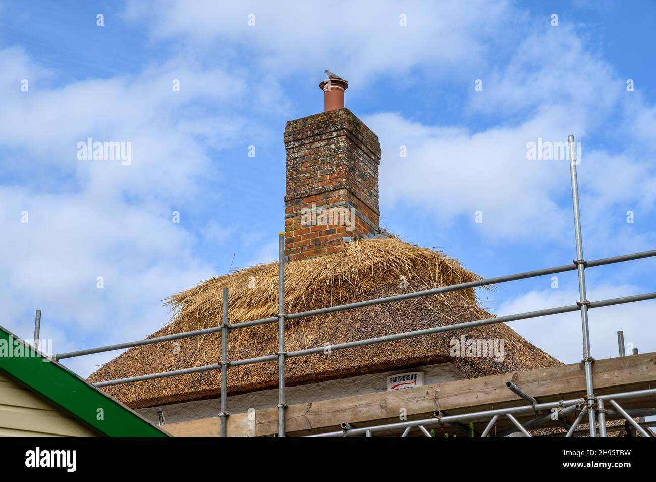 Cottage con ponteggio eretto per la manutenzione e la riparazione di un tetto di paglia nel villaggio di Farnham, Dorset, Inghilterra. Foto Stock