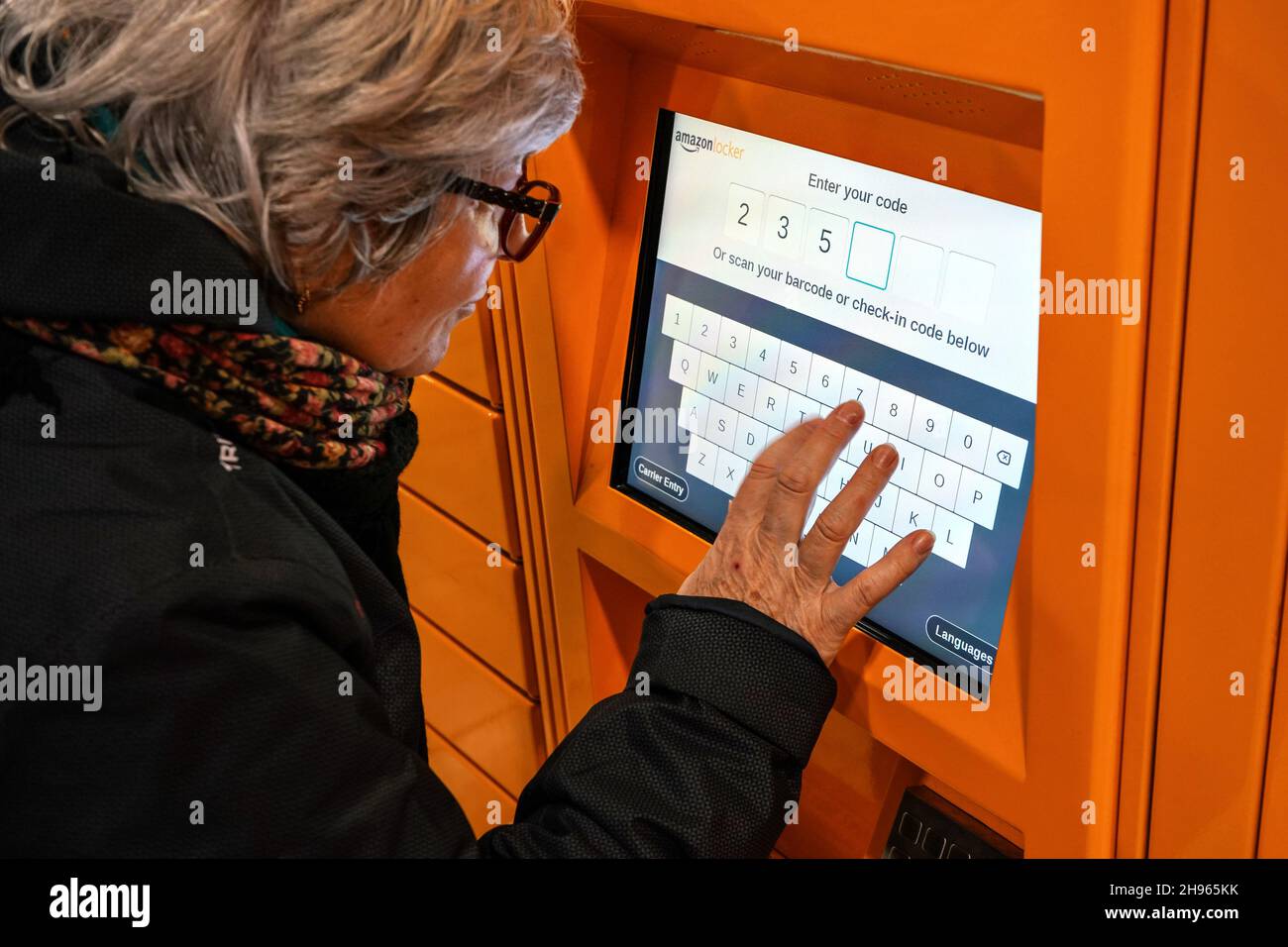 Londra, Regno Unito - 04 febbraio 2019: Donna anziana che immette il codice al chiosco self-service Orange Amazon (rivenditore online), closeup sulla sua h Foto Stock