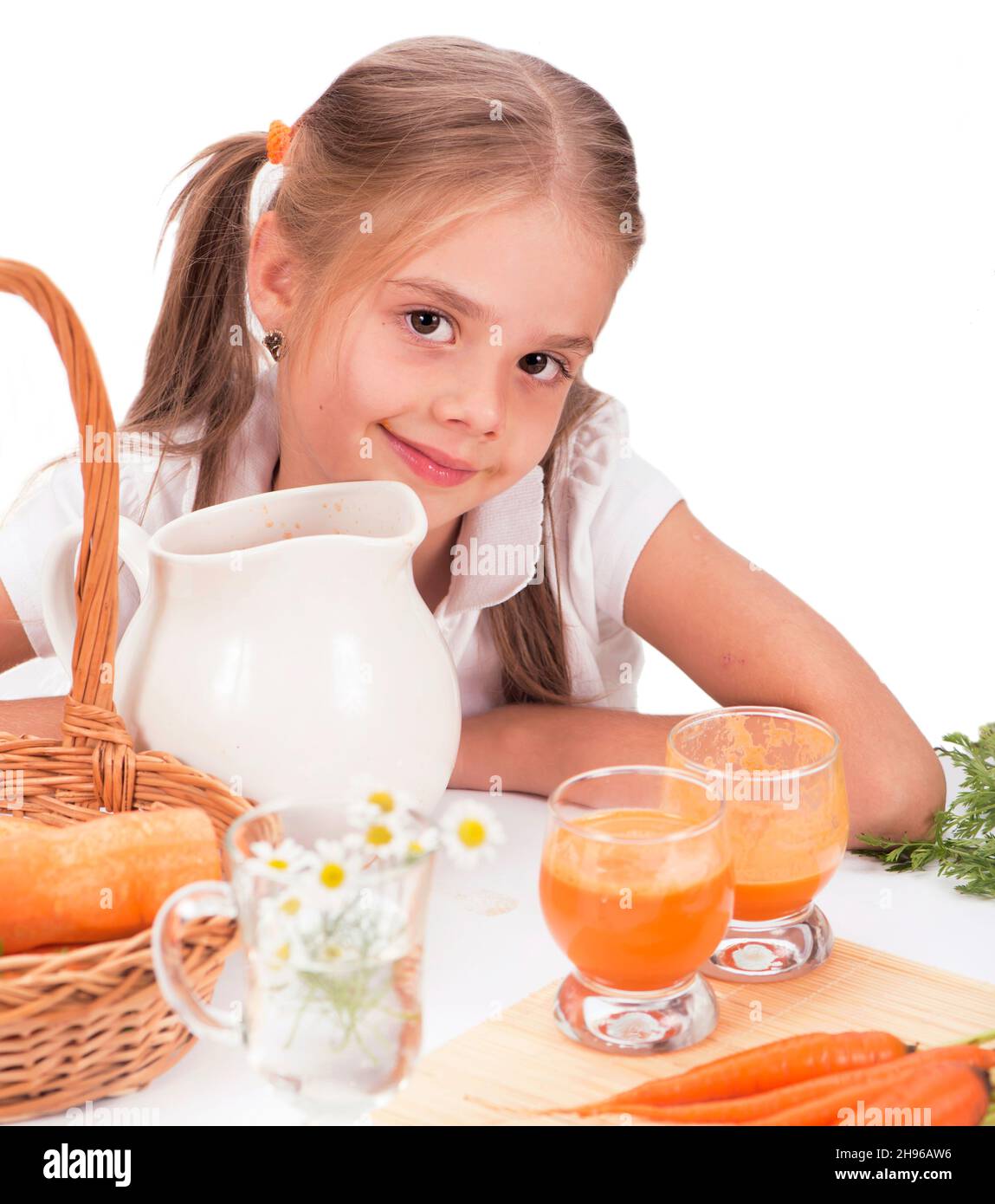 Carino bambina bere succo di carota. Sfondo bianco Foto Stock