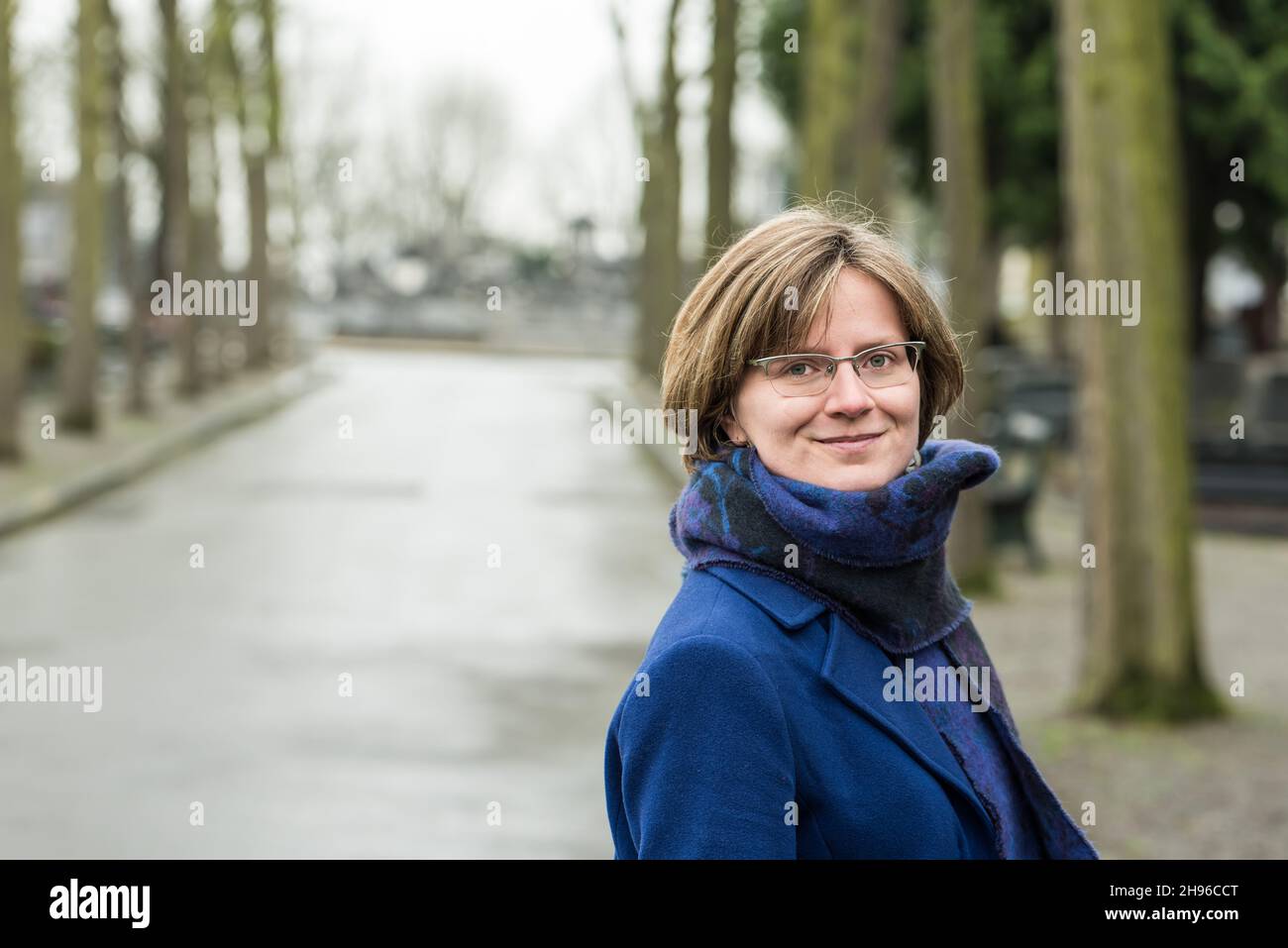 Attraente donna di trent'anni che guarda fiduciosa nell'obiettivo,  indossando una sciarpa e un cappotto blu Foto stock - Alamy