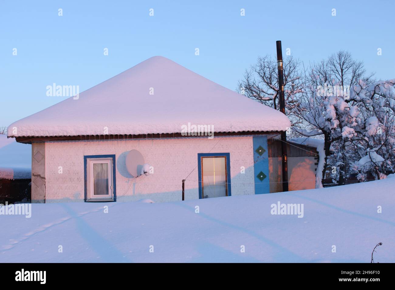 Vecchia casa di villaggio coperta di neve. Spesso strato di neve sul tetto. Foto Stock