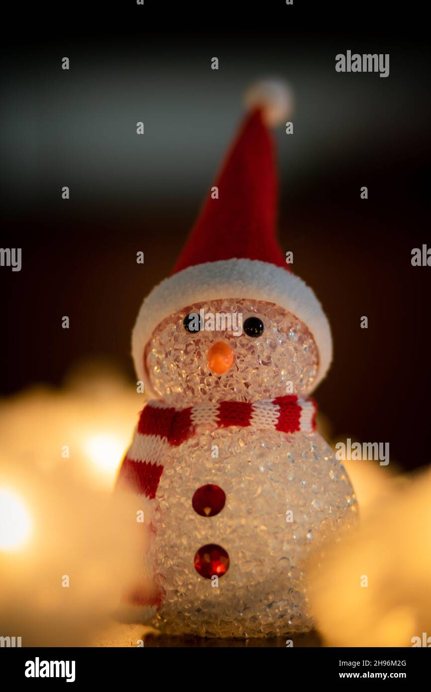 Primo piano della statuetta di Natale con un cappello Babbo Natale e  sciarpa rossa e bianca illuminata da luci offuscate di fata dorata Foto  stock - Alamy