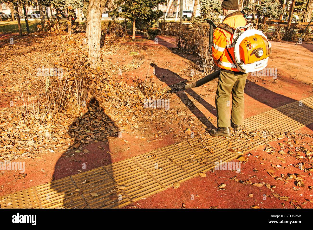 Dnepropetrovsk, Ucraina - 11.25.2021: Pulizia di foglie secche con un mulino a vento. Un lavoratore municipale pulisce il parco cittadino. Preparazione dei parchi cittadini per l'inverno Foto Stock