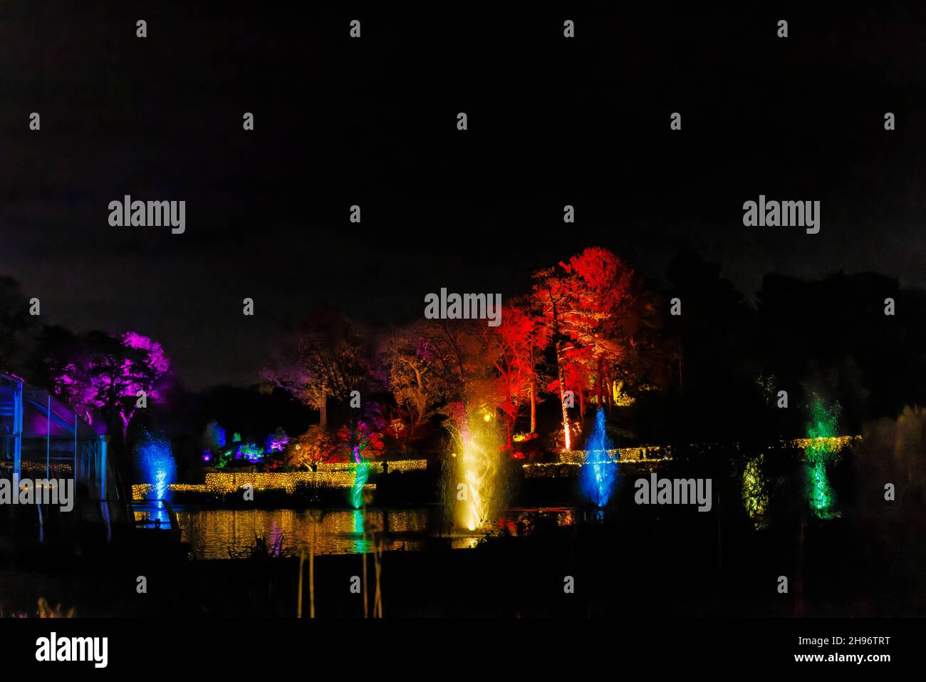 Fontane dai colori vivaci nel lago a Glow 2021, l'evento annuale di luci natalizie al RHS Garden, Wisley, Woking, Surrey Foto Stock