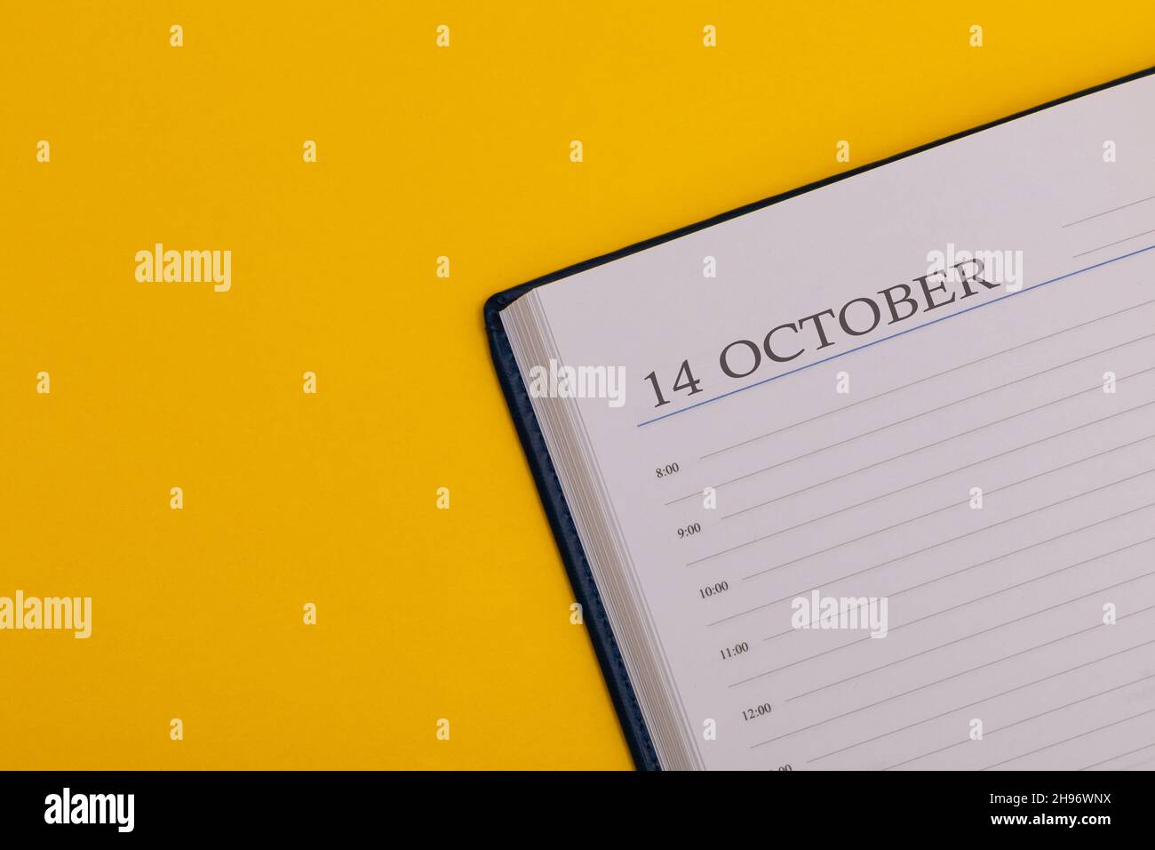 Blocco note o agenda con la data esatta su sfondo giallo. Calendario del 14 ottobre - ora di autunno. Spazio per il testo. Foto Stock