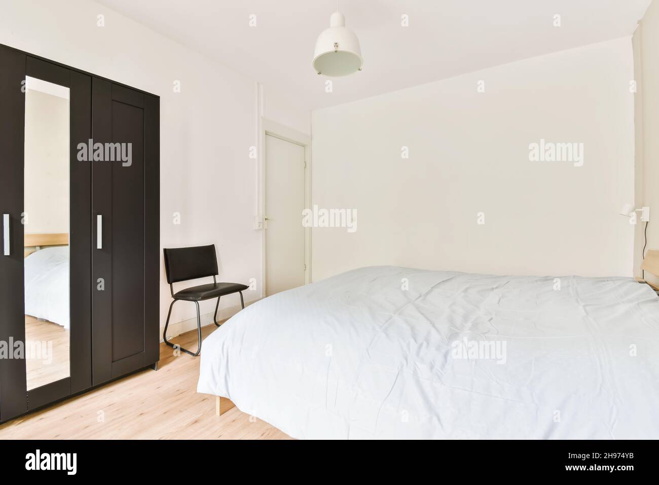 Una camera da letto alla luce del giorno con una morbida copertura di sintetizzatore monocromatica blu Foto Stock
