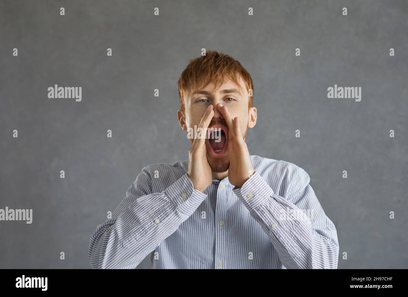 Foto di un uomo urlante con palme sul viso e bocca aperta Foto Stock