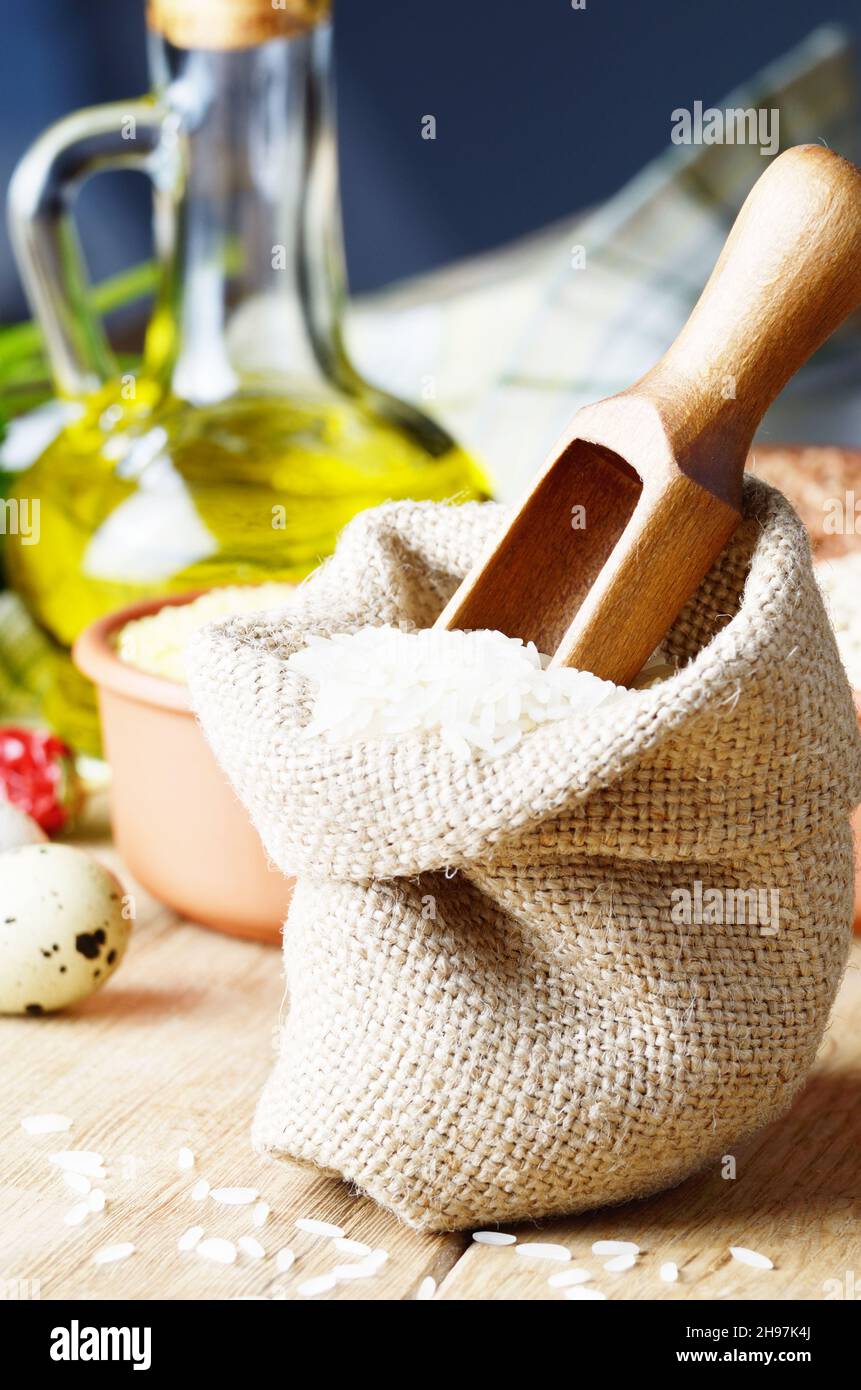 Grani di riso biologico in sacco di burlap sul tavolo da cucina con ingredienti alimentari Foto Stock