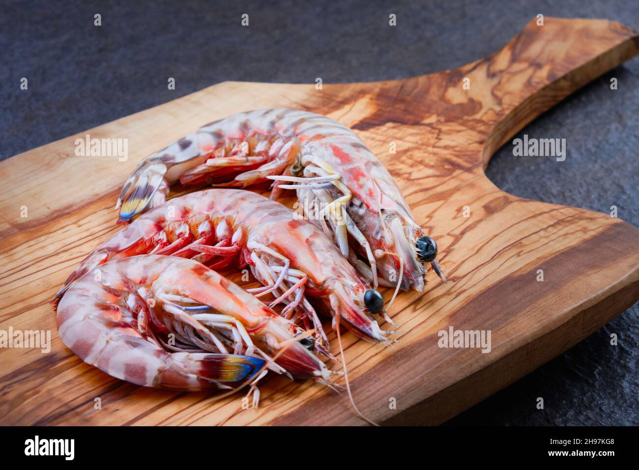 Gamberi crudi su tagliere di legno Foto Stock